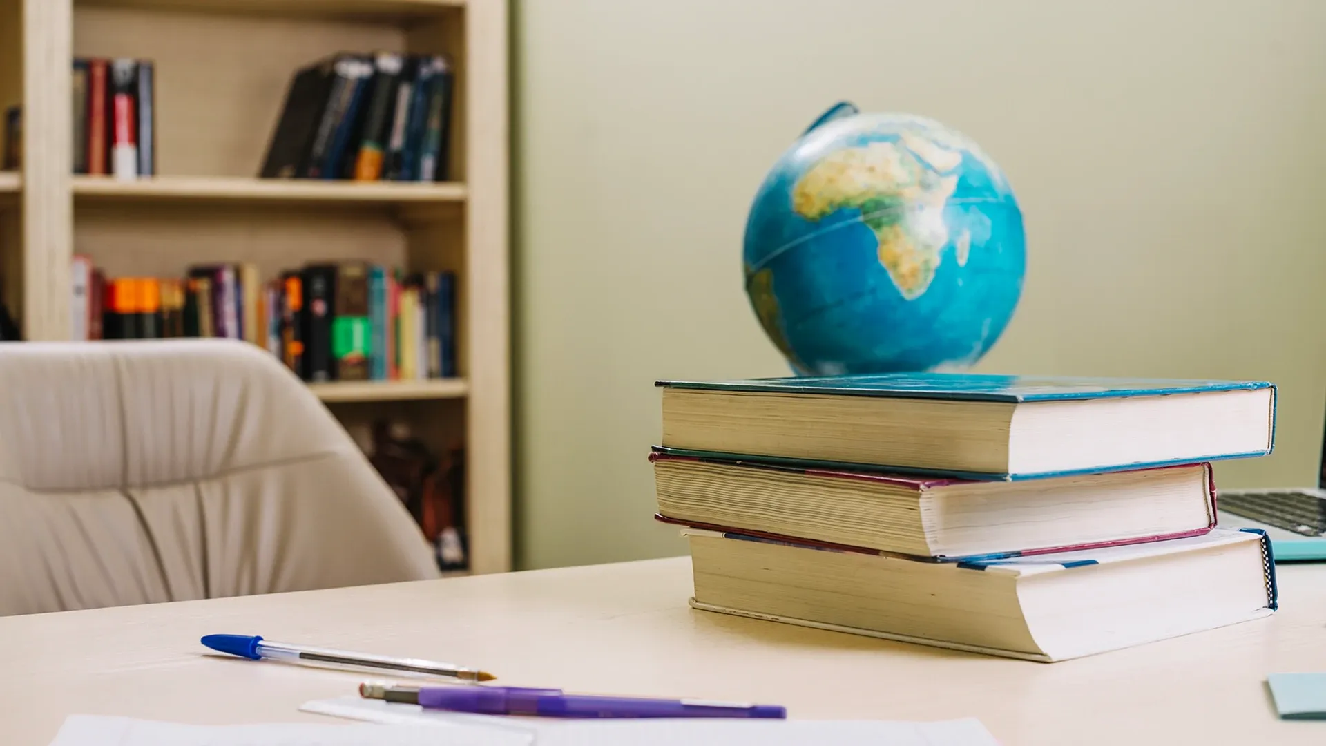  Detalle de un escritorio con libros y globo terraqueo. 